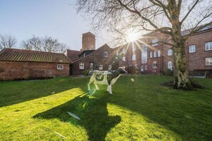 A courtyard with a cow sculpture, brick buildings, and a tree. - Holiday apartment with 1 bedroom (Borkum)