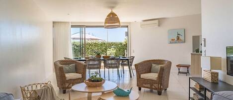 Una sala moderna con muebles de mimbre, un comedor y un televisor.