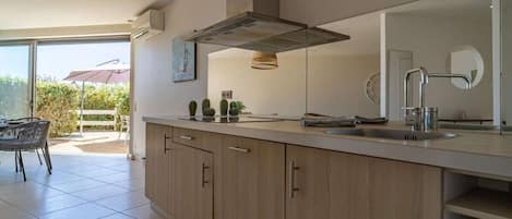 Una cocina moderna con una isla grande, horno empotrado y ventana con vistas a un patio.