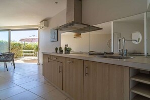 A modern kitchen with a large island, a built-in oven, and a window overlooking a patio area. - in "La Grande Motte" for 6 people (La Grande-Motte)