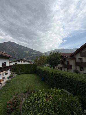 A residential area with multiple buildings, a well-maintained lawn, and a mountainous backdrop.