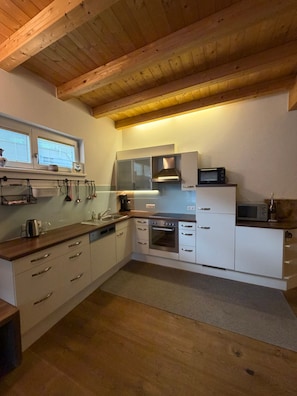 Een keuken met houten balken in het plafond, een magnetron, oven en een raam boven de spoelbak.