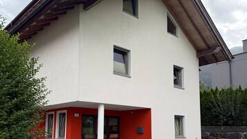 Ein zweigeschossiges Gebäude mit einer roten und weißen Fassade, zahlreichen Fenstern und einer Steinsäule im Hintergrund.