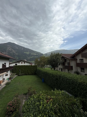A residential area with multiple buildings, a well-maintained lawn, and a mountainous backdrop.