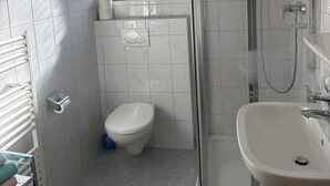 Kylpyhuone, jossa on wc, suihkukaappi ja pesuallas.