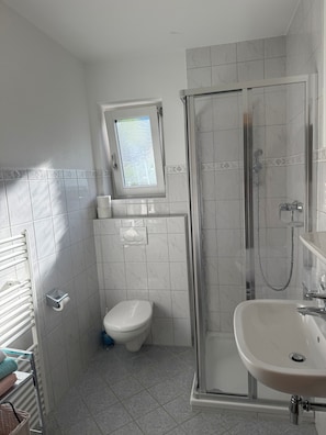 Un baño con inodoro, cabina de ducha y lavamanos.