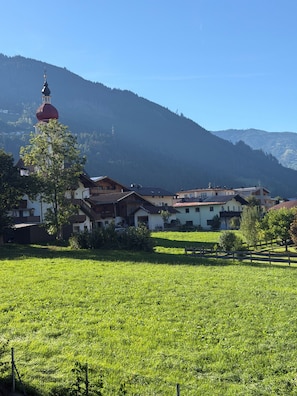 A rural village with traditional houses, a church with a red dome, and a mountain backdrop.