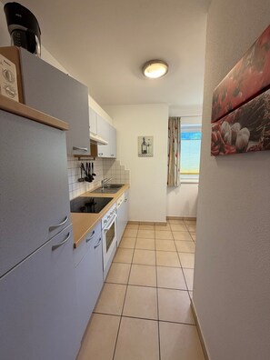 A compact kitchen with a refrigerator, stove, sink, and cabinets. - Apartment Markus: Gartenwohnung mit Bergblick, privatem Garten, WLAN & Spa (gegen Aufpreis) (Ried im Zillertal)