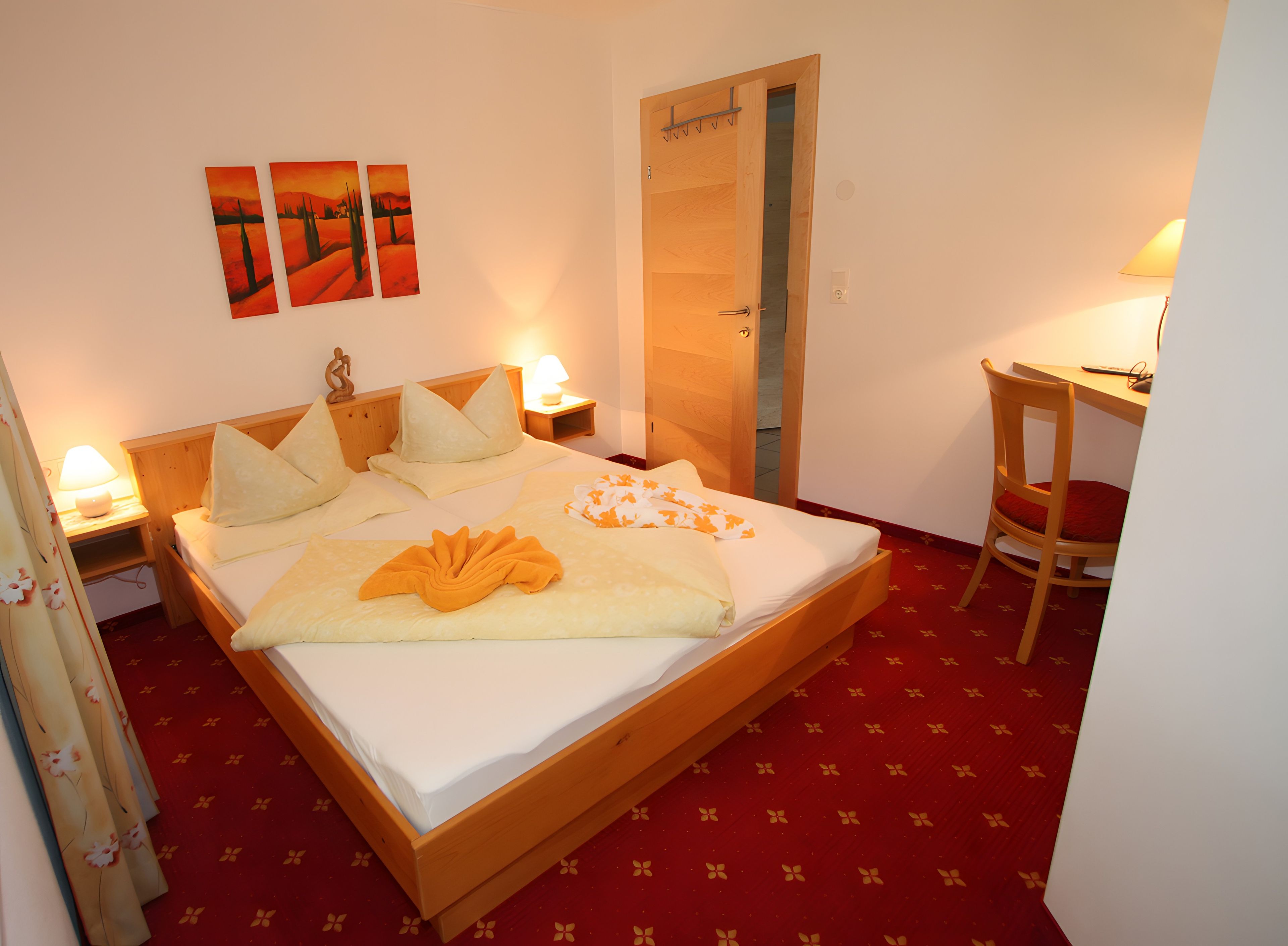 Ein Hotelzimmer mit Bett, Nachttischen, Schreibtisch und Stuhl.