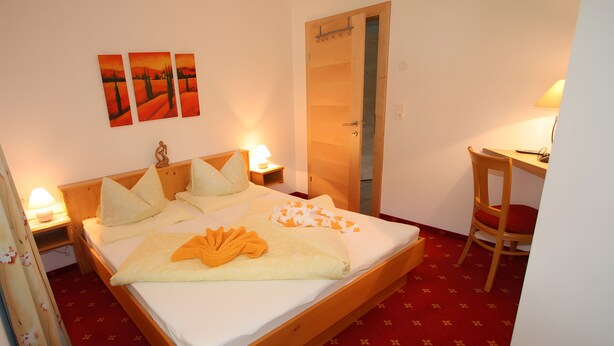 A hotel room with a bed, bedside tables, a desk, and a chair. - Apartment Markus: Gartenwohnung mit Bergblick, privatem Garten, WLAN & Spa (gegen Aufpreis) (Ried im Zillertal)