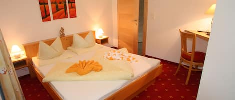 Una habitación de hotel con una cama, mesitas de noche, un escritorio y una silla.
