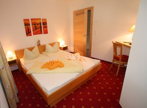 A hotel room with a bed, bedside tables, a desk, and a chair. - Apartment Markus: Gartenwohnung mit Bergblick, privatem Garten, WLAN & Spa (gegen Aufpreis) (Ried im Zillertal)