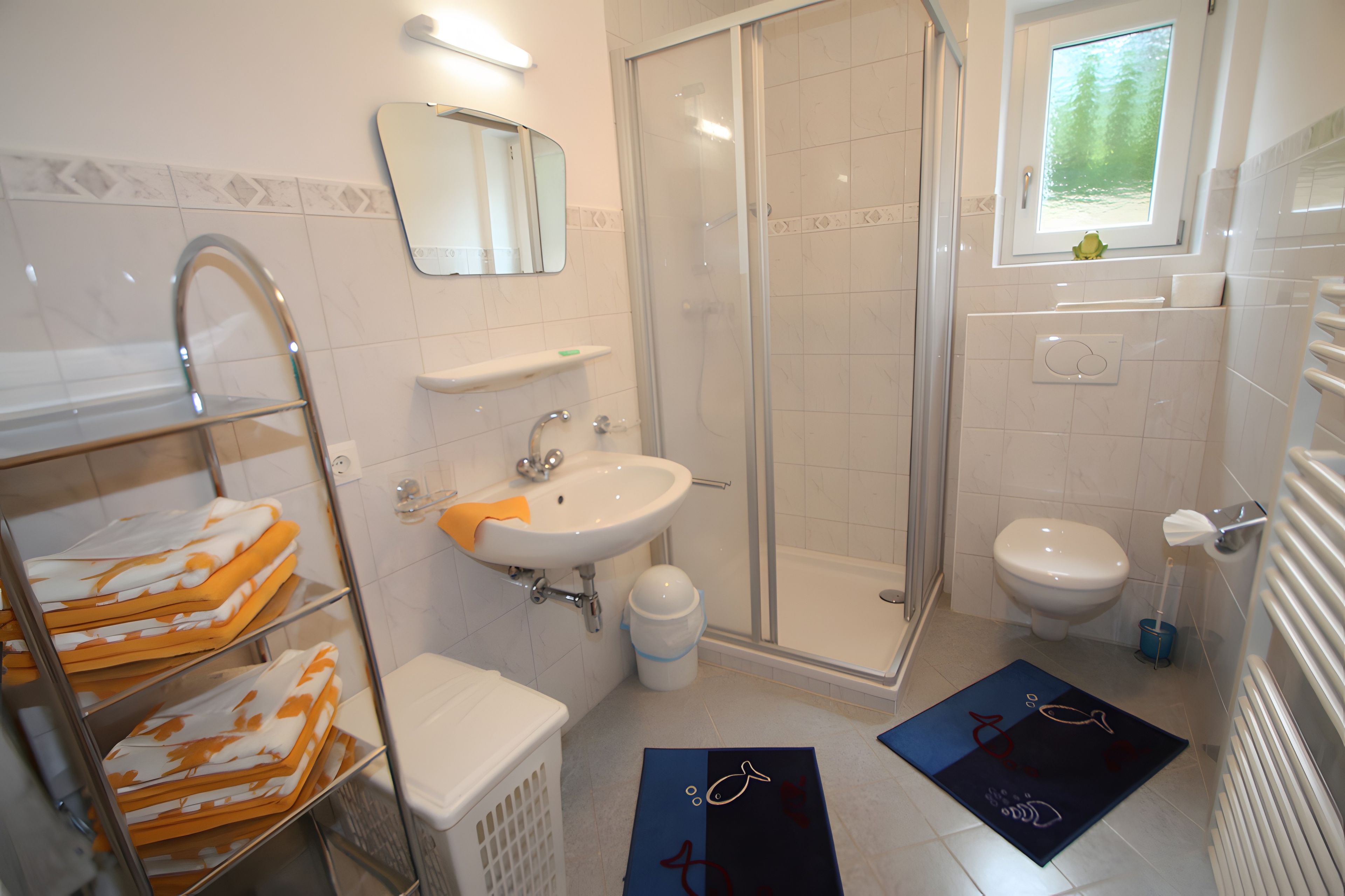 Ein Badezimmer mit Dusche, Waschbecken, Toilette und einem Handtuchhalter mit Handtüchern.