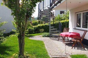 Un patio con una mesa, sillas, un árbol y un edificio con escaleras.