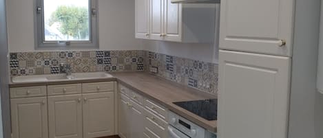 A kitchen with white cabinets, a window, and patterned floor tiles.