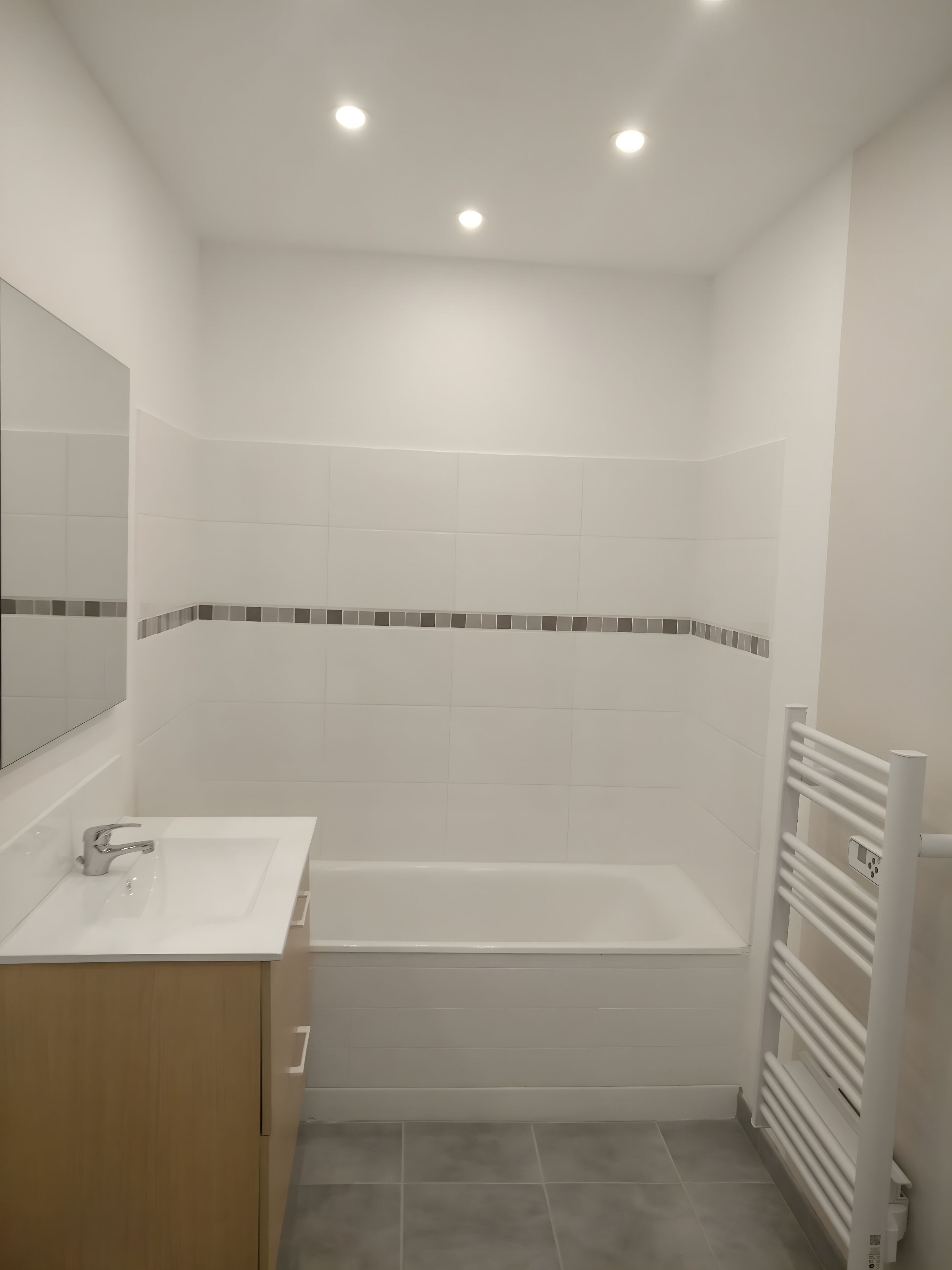 Une salle de bain avec un lavabo blanc, un miroir et une baignoire.