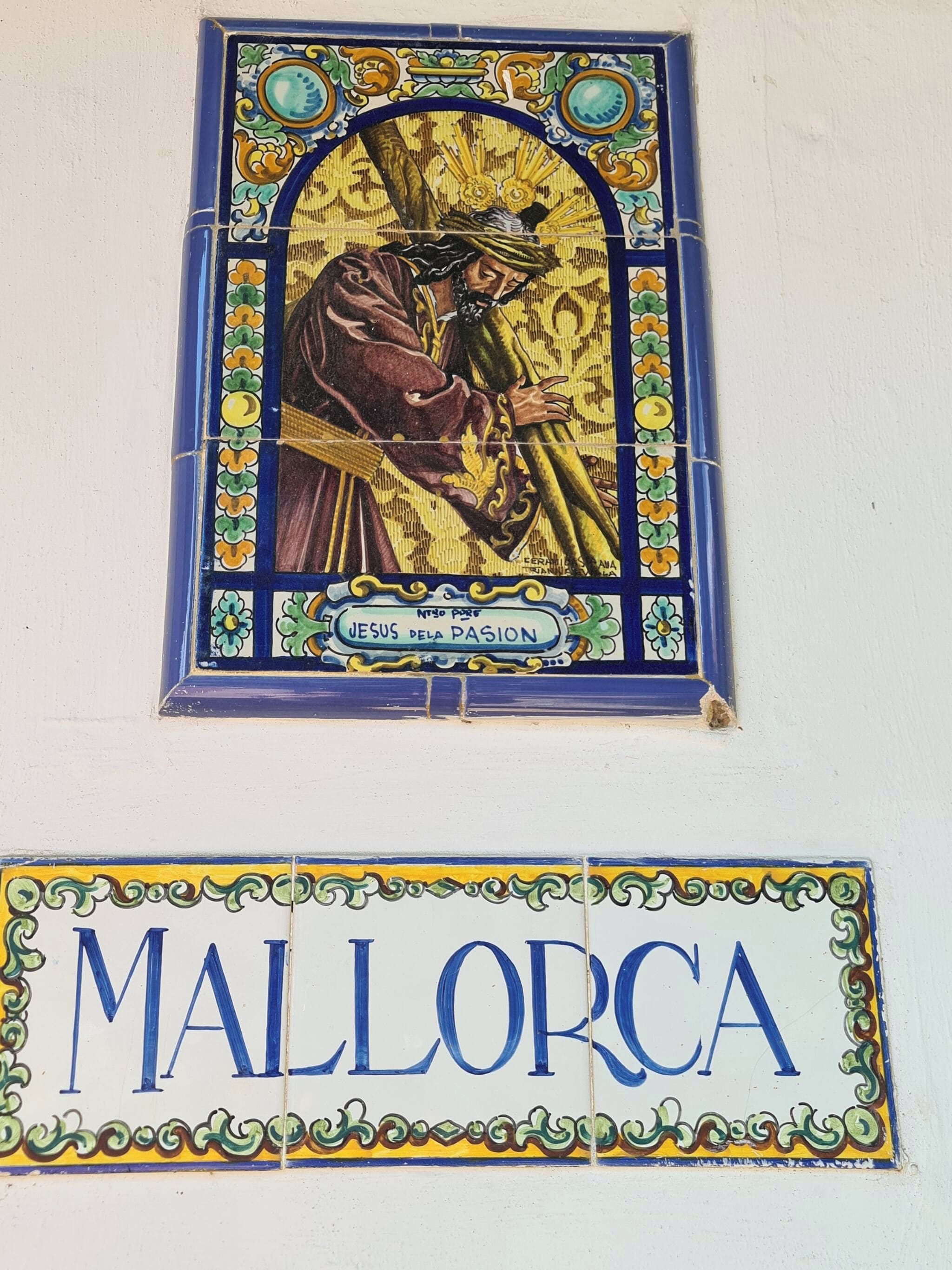 A stained glass window with a figure and the inscription 'JESUS FLETA PASCION' and a sign below reading 'MALLORCA'.