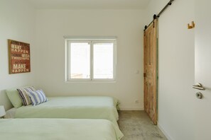 Een slaapkamer met twee bedden, een raam en een houten deur.