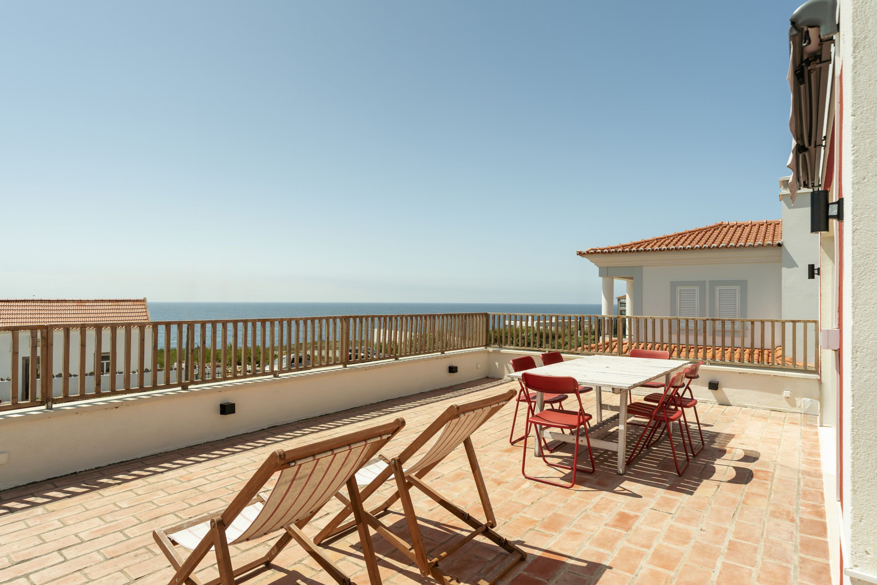 Une terrasse avec une table et des chaises, donnant sur une étendue d’eau.