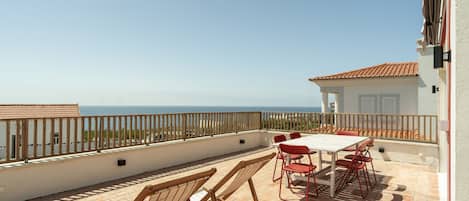 A terrace with a table and chairs, overlooking a body of water.