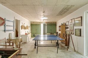 Una habitación con mesa de ping pong, un mueble de madera y varias fotos enmarcadas en las paredes.