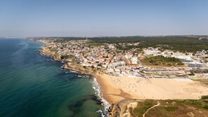 An aerial view of a coastal town with a beach, buildings, and a clear sky. - The Red House by Cadenzalux (Sintra)