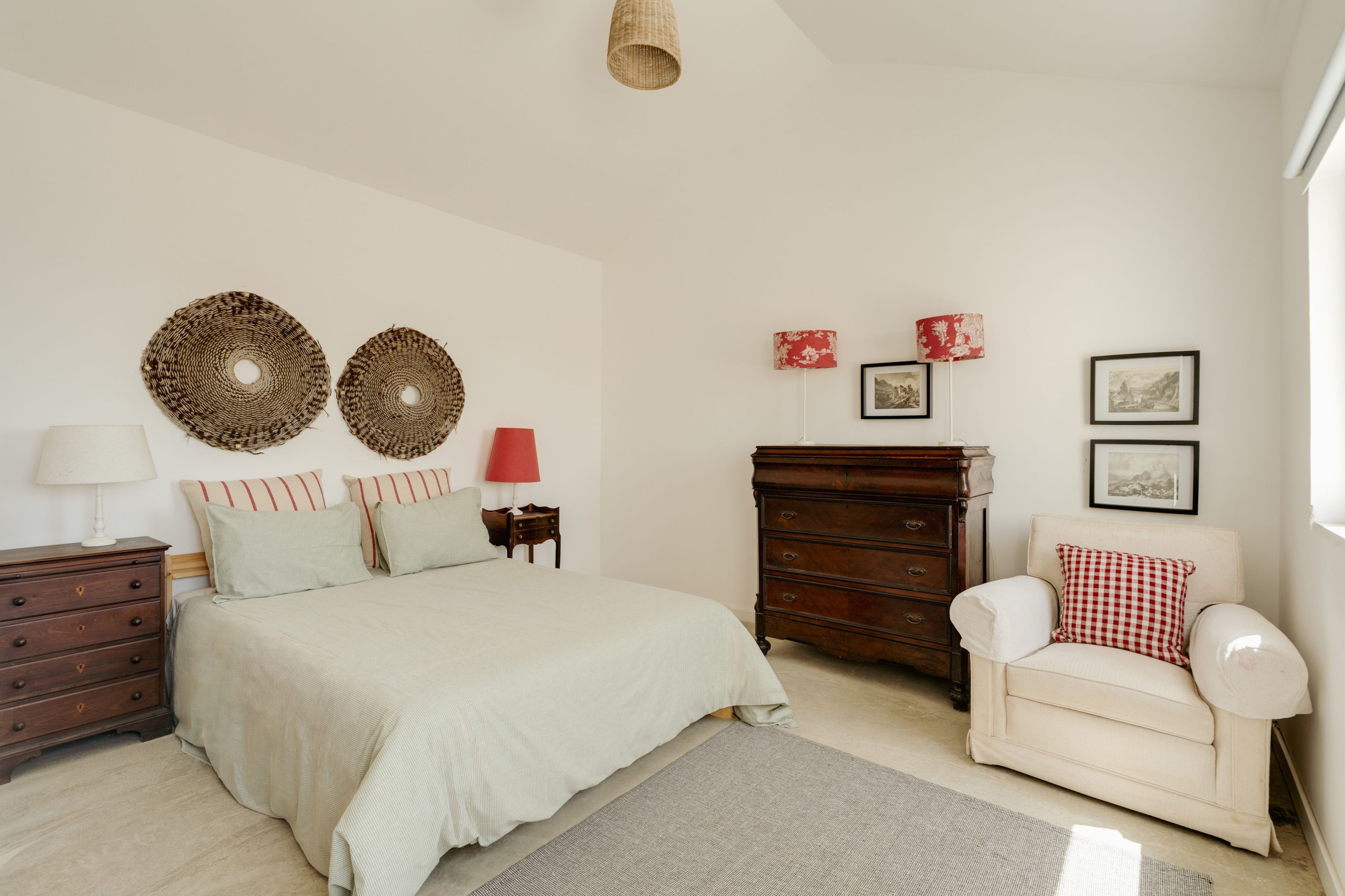 Quarto com cama, penteadeira, cadeira, luminária e decorações nas paredes.