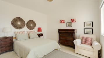 Quarto com cama, penteadeira, cadeira, luminária e decorações nas paredes.