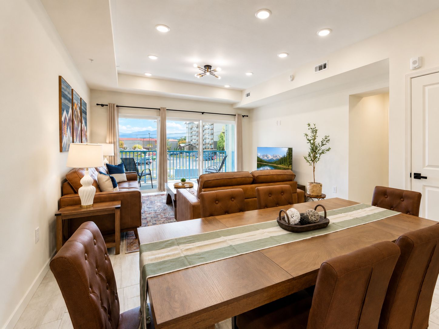 A spacious living area with a dining table, sofas, and a view of the outdoors.