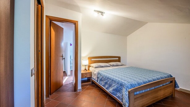 A bedroom with a wooden bed, a nightstand, and a door leading to another room. - The Hedgehog Trail (Sicignano degli Alburni)