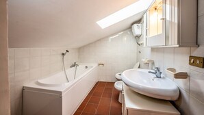 A modern bathroom with a bathtub, toilet, and sink, featuring white fixtures and a sloped ceiling with skylight. - The Hedgehog Trail (Sicignano degli Alburni)