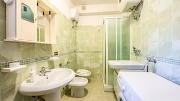 Une salle de bain équipée d’un lave-linge, de deux éviers, de toilettes et d’une cabine de douche.