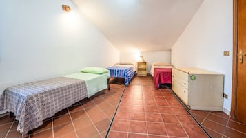 Una piccola camera mansardata a forma di triangolo con due letti, una cassettiera e una porta.