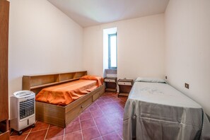 A small, single-room accommodation with a bed, a desk, and a heater.