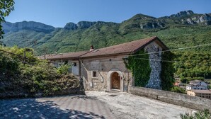 A stone building with a tiled roof, an arched entrance, and a view of a mountainous landscape. - The Hedgehog Trail (Sicignano degli Alburni)
