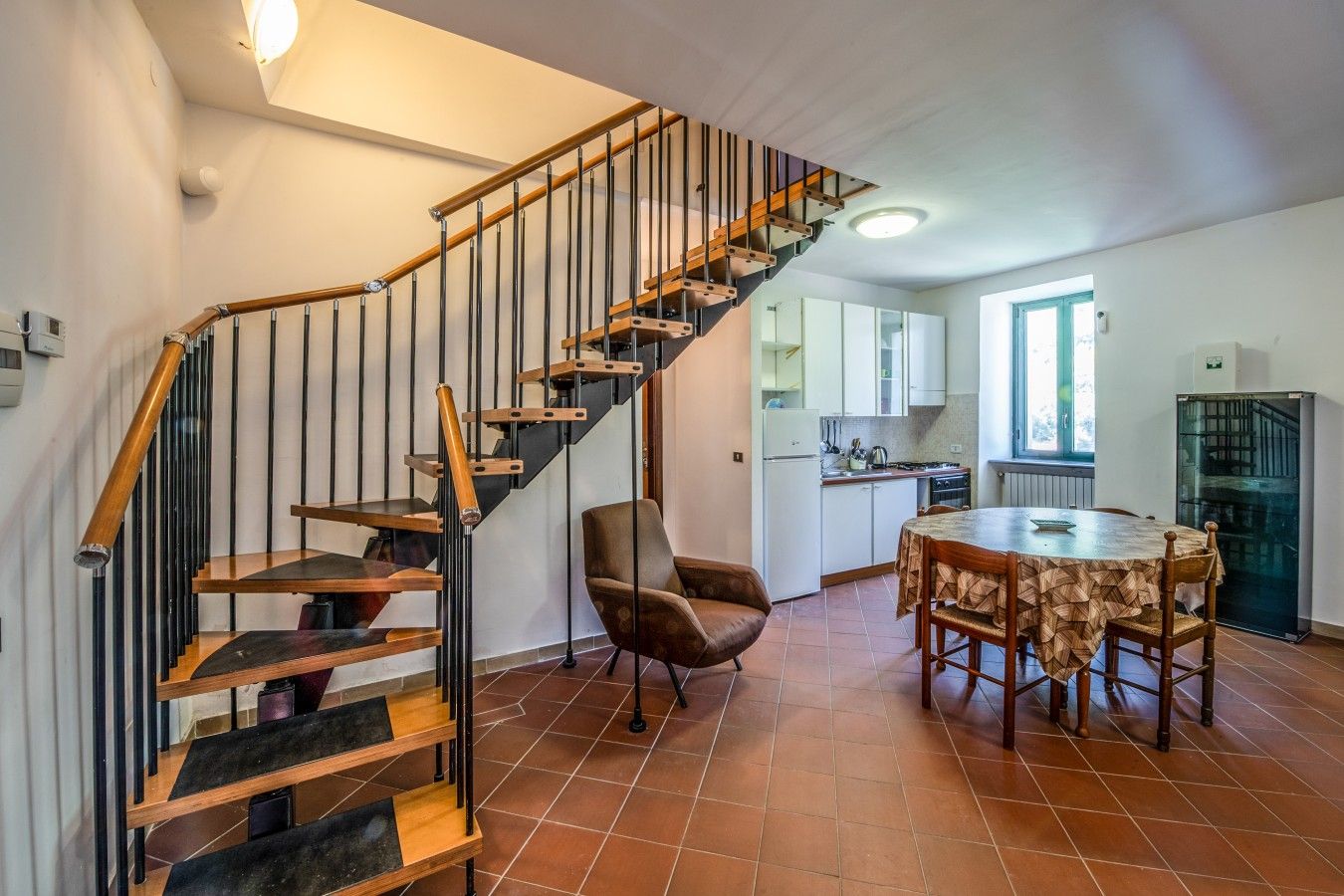 Eine moderne Küche mit einer Wendeltreppe, einem Essbereich mit einem runden Tisch und einem Stuhl.
