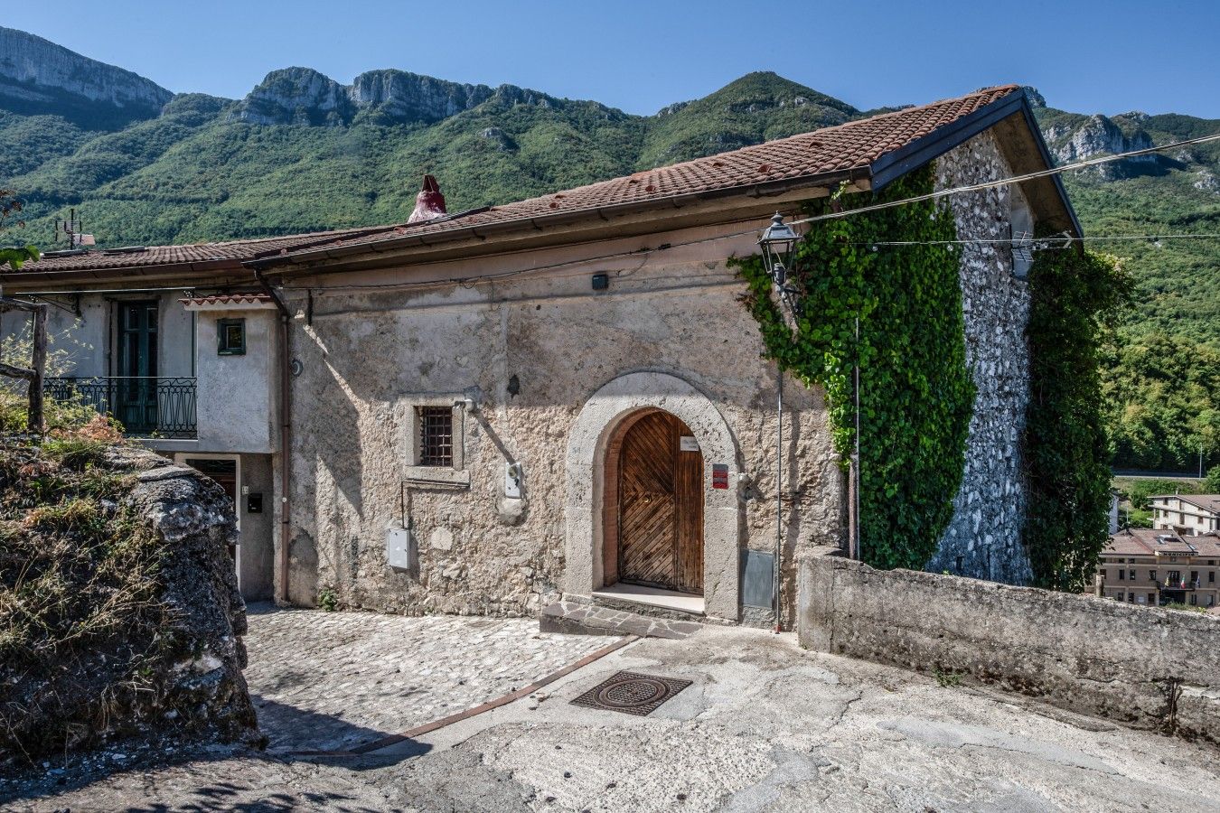 Un bâtiment traditionnel en pierre, avec un toit en tuiles, une entrée en arc de cercle et une petite fenêtre.
