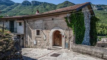 Un bâtiment traditionnel en pierre, avec un toit en tuiles, une entrée en arc de cercle et une petite fenêtre.