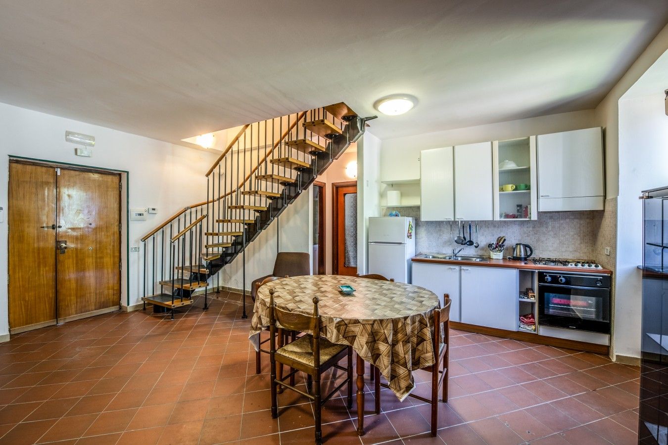 Una cucina con zona pranzo, una scala e un frigorifero.