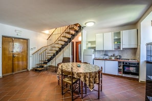 A kitchen with a dining area, a staircase, and a refrigerator.