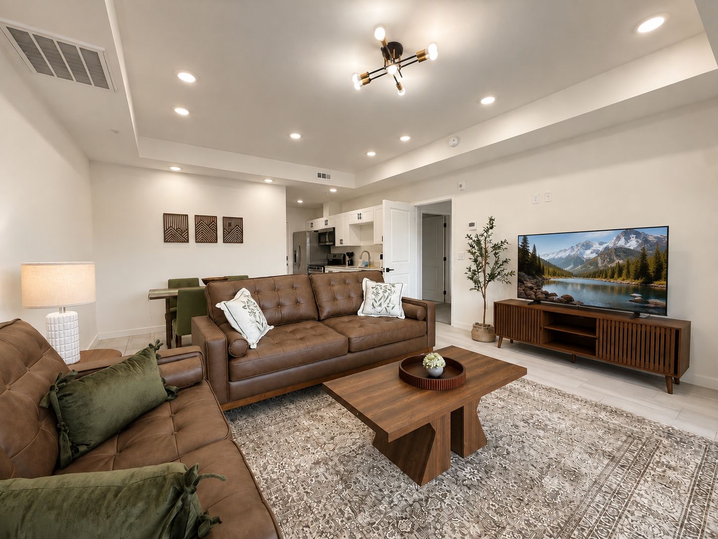 A modern living room with a brown leather sofa, a wooden coffee table, and a flat-screen TV on a wooden stand.