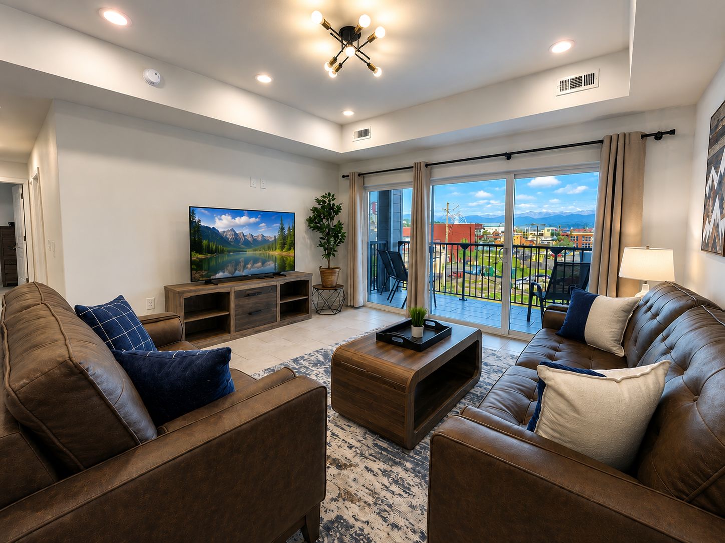 A modern living room with a large flat-screen TV, leather sofas, a wooden coffee table, and a balcony with a view of the city.