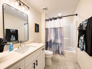 Een badkamer met een wastafel, spiegel, toilet en douchegordijn.
