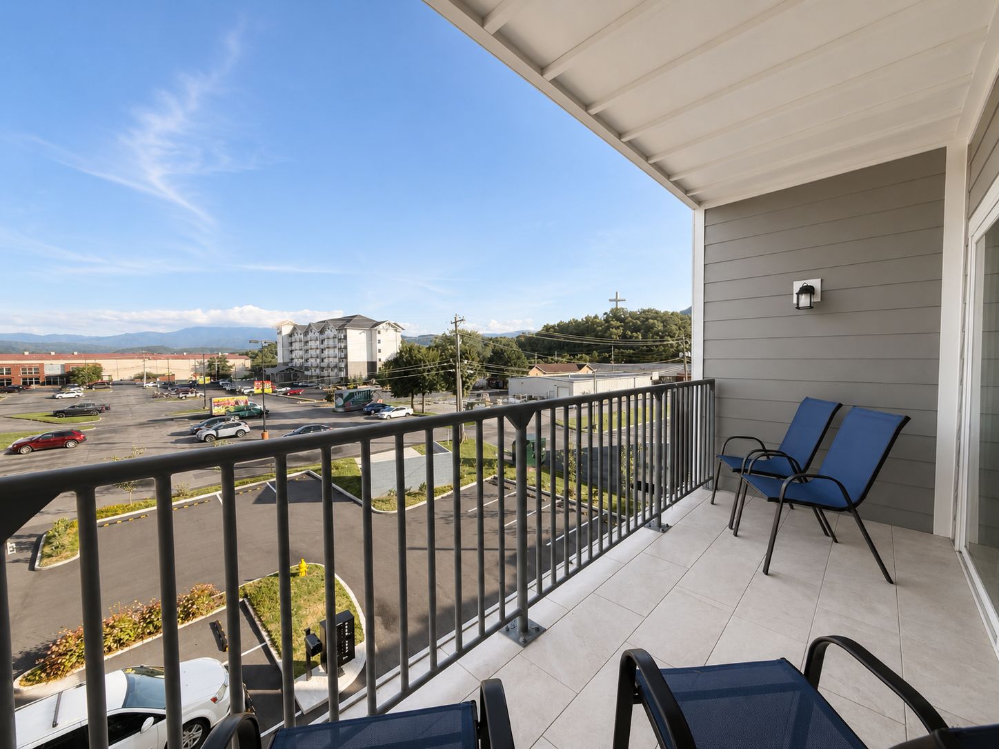 Un balcon donnant sur un parking et des immeubles.