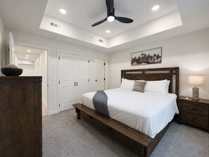 Ein Schlafzimmer mit Bett, Nachttisch, Lampe und Deckenventilator.