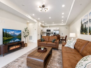 A modern living room with a fireplace, leather sofas, a coffee table, and a television. - New Pigeon Forge Condo | Island View (Pigeon Forge)