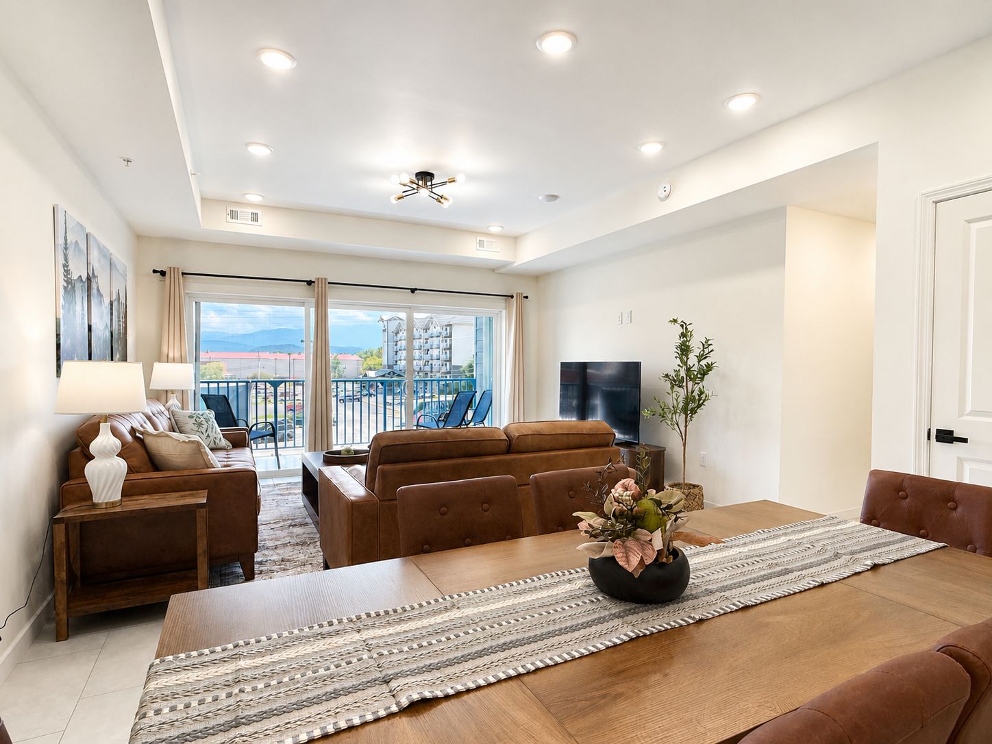 A spacious living area with a sofa set, a dining table, and a TV.