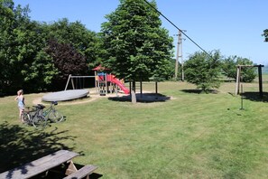 A playground with a slide and swings, a picnic table, and bicycles. - Holiday apartment with 2 bedrooms (Amelinghausen)