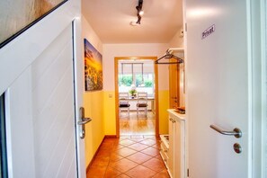 A hallway with a tiled floor, a dining area with a table and chairs, and a kitchen area with cabinets and a stove. - Holiday apartment with 2 bedrooms (Amelinghausen)