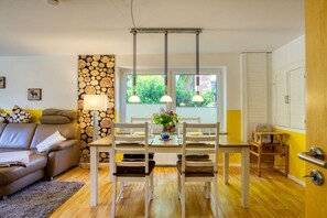 A dining area with a wooden table and chairs, a vase with flowers, and a stone wall. - Holiday apartment with 2 bedrooms (Amelinghausen)